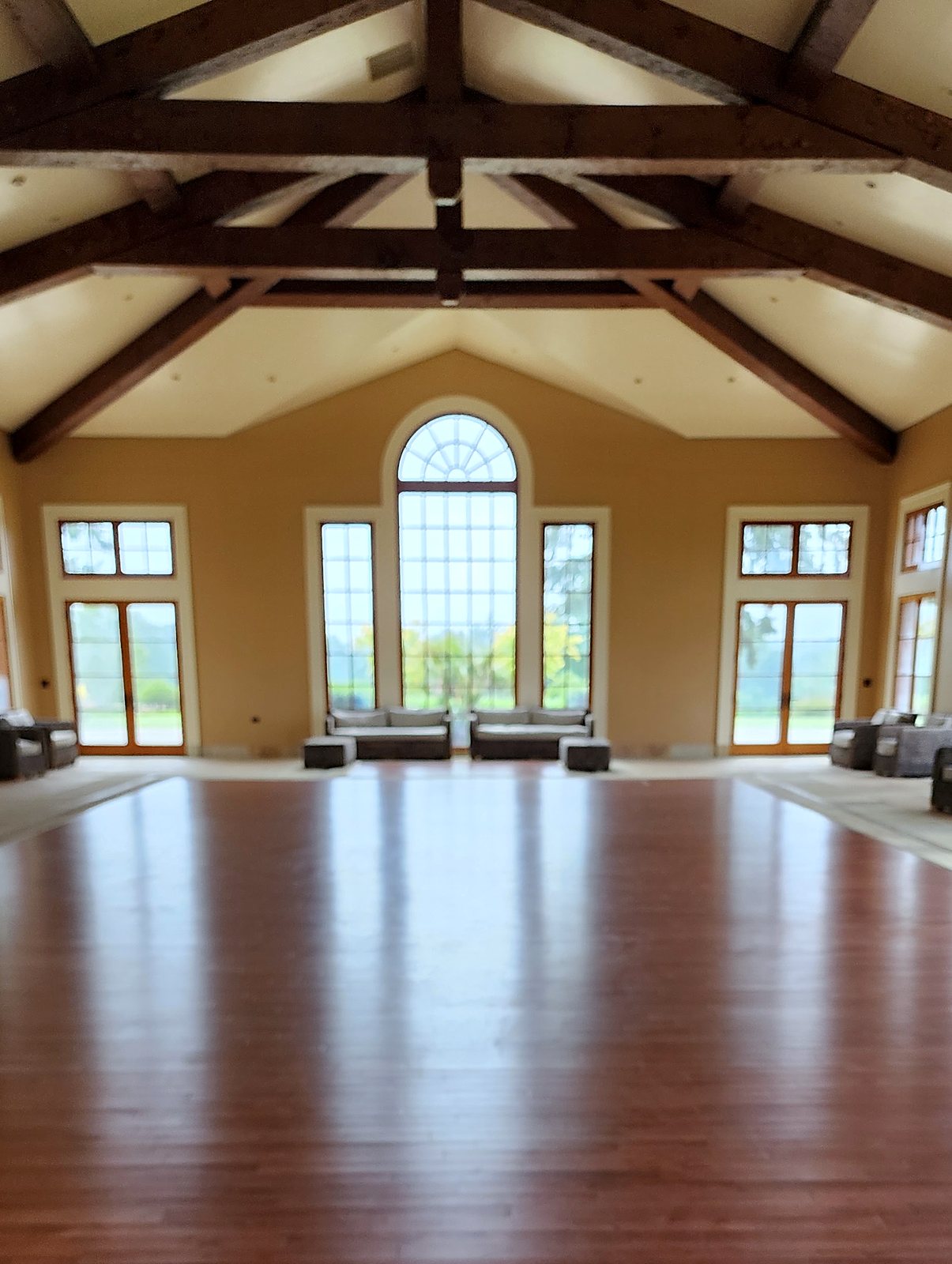 Large empty hall with beamed ceiling and wood floor