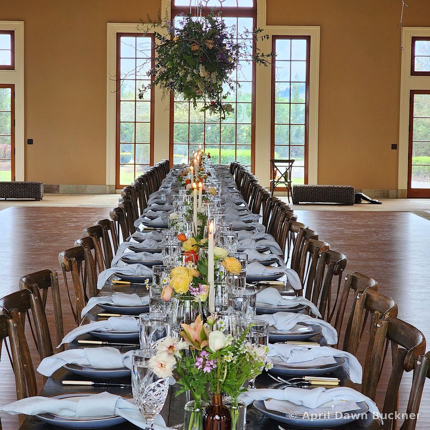 Looking down the length of a long set table with gray napkins, white plates and low flowers