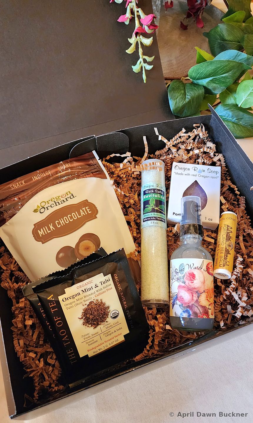 A gift box of packaged goods nested in shredded paper