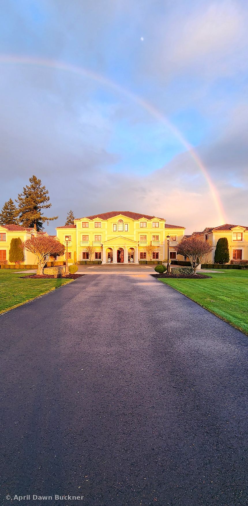 The drive leading straight to the front of the villa, with a faint rainbow in the cloudy sky