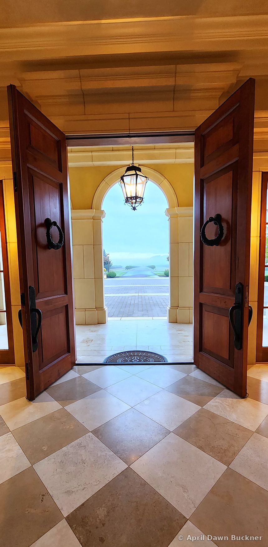 Through open dark-wood double doors to an arched porch, with a checkered floor inside