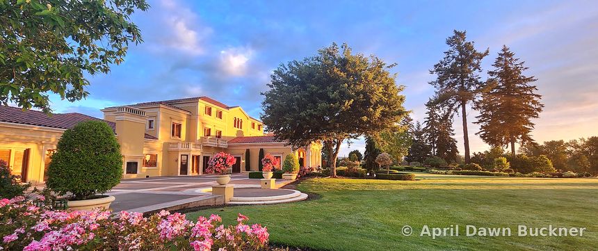 The villa and the wide lawn seen over rose borders, under a sunrise sky