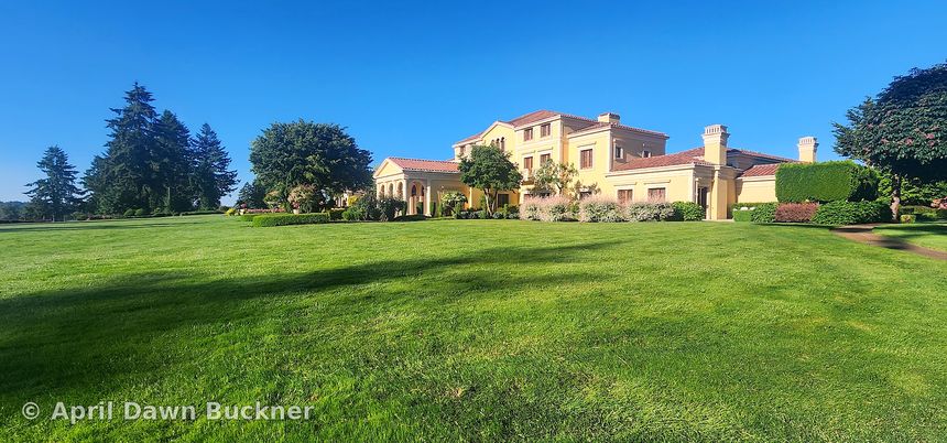 The villa and its red tile roof across a wide lawn under a clear blue sky