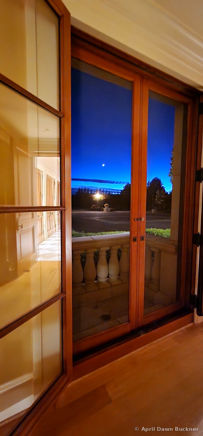 Through wooden French doors at dusk, with a crescent moon in the deep blue sky