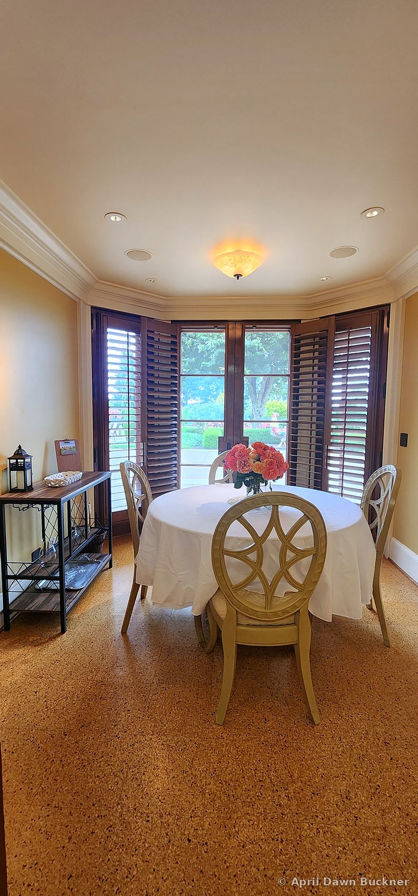 A round table with a white cloth and chairs in a bay-window nook
