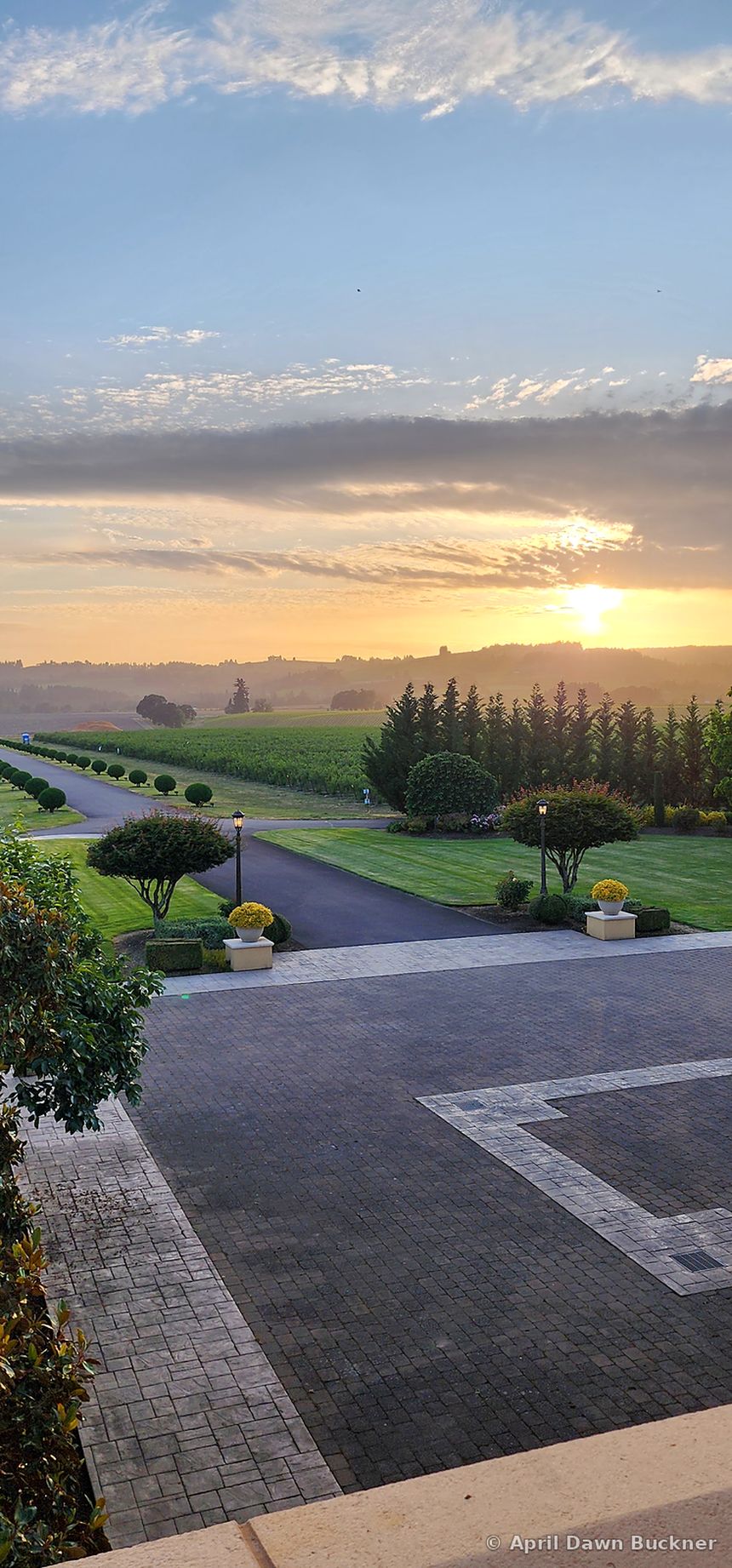 The paved courtyard, lawn and rolling hills seen from high up at sunset