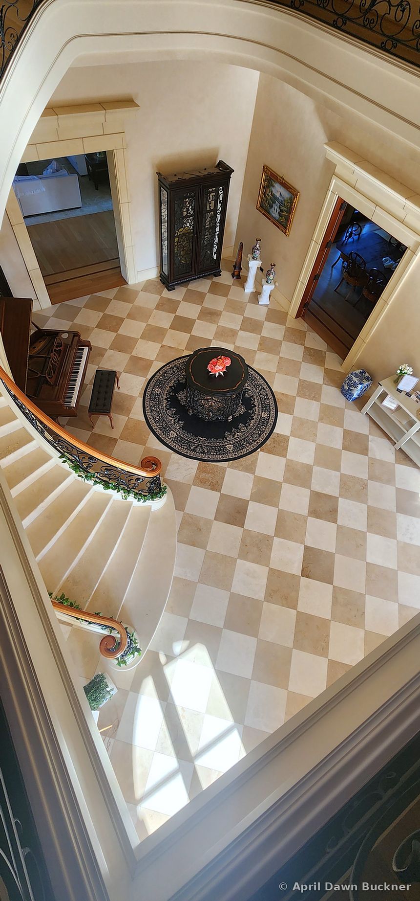 Looking down the curve of the staircase to the checkered foyer floor
