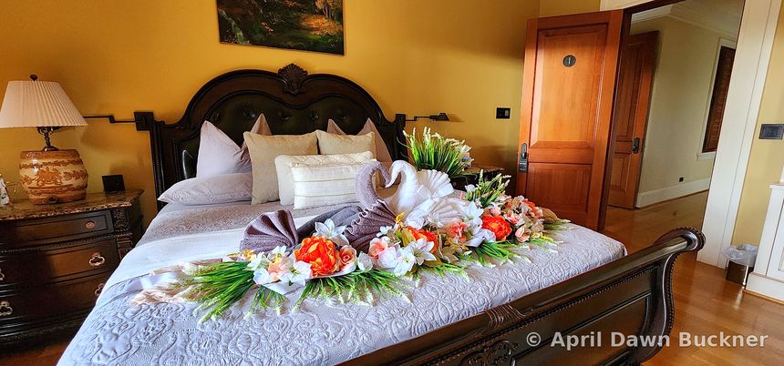 A wider view of the decorated bed in its room, with a bedside table and a door