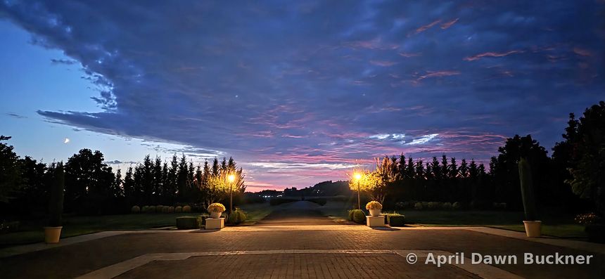 The stone patio at dusk with lamp posts under a cloudy sky